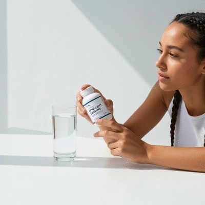 Person holding a bottle of stimulant laxatives with a glass of water on a clean background, no text, no words, no typography, clean image