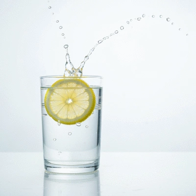 Glass of water with a slice of lemon on a clean background